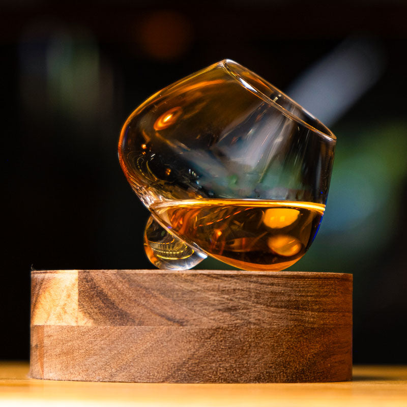 Bicchiere da distillato in cristallo Aequilibrium di Audacem su sottobicchieri per whisky, liquori e distillati. Design rotante.