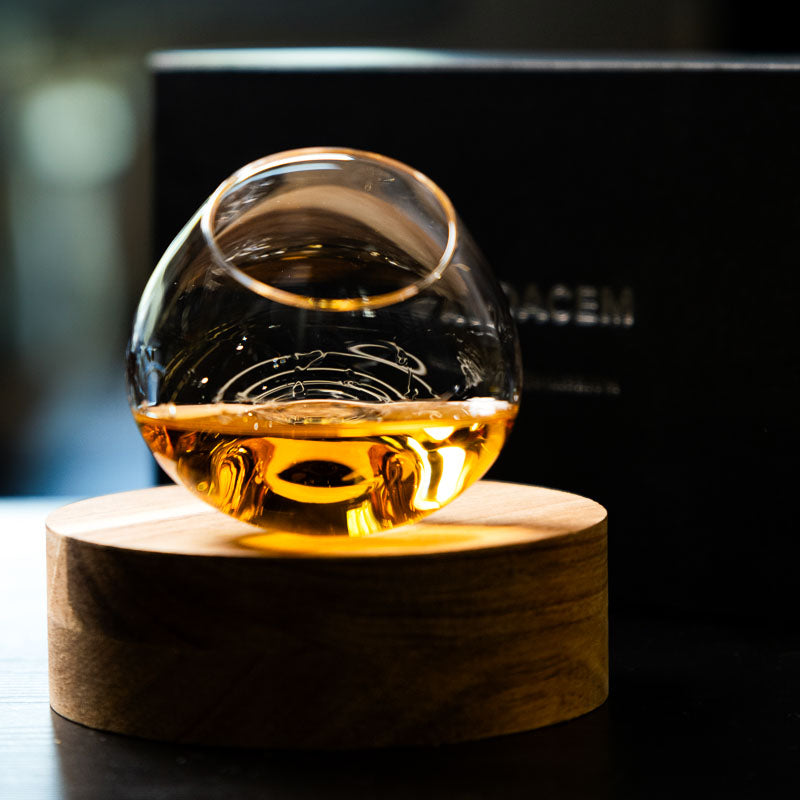 Elegante bicchiere da distillato Aequilibrium di Audacem su sottobicchiere per whisky, liquori e distillati. Design rotante.