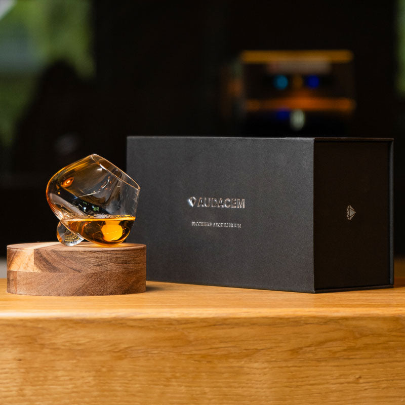 Elegante bicchiere da distillato Aequilibrium soffiato a mano di Audacem su sottobicchiere con confezione regalo. Design rotante.